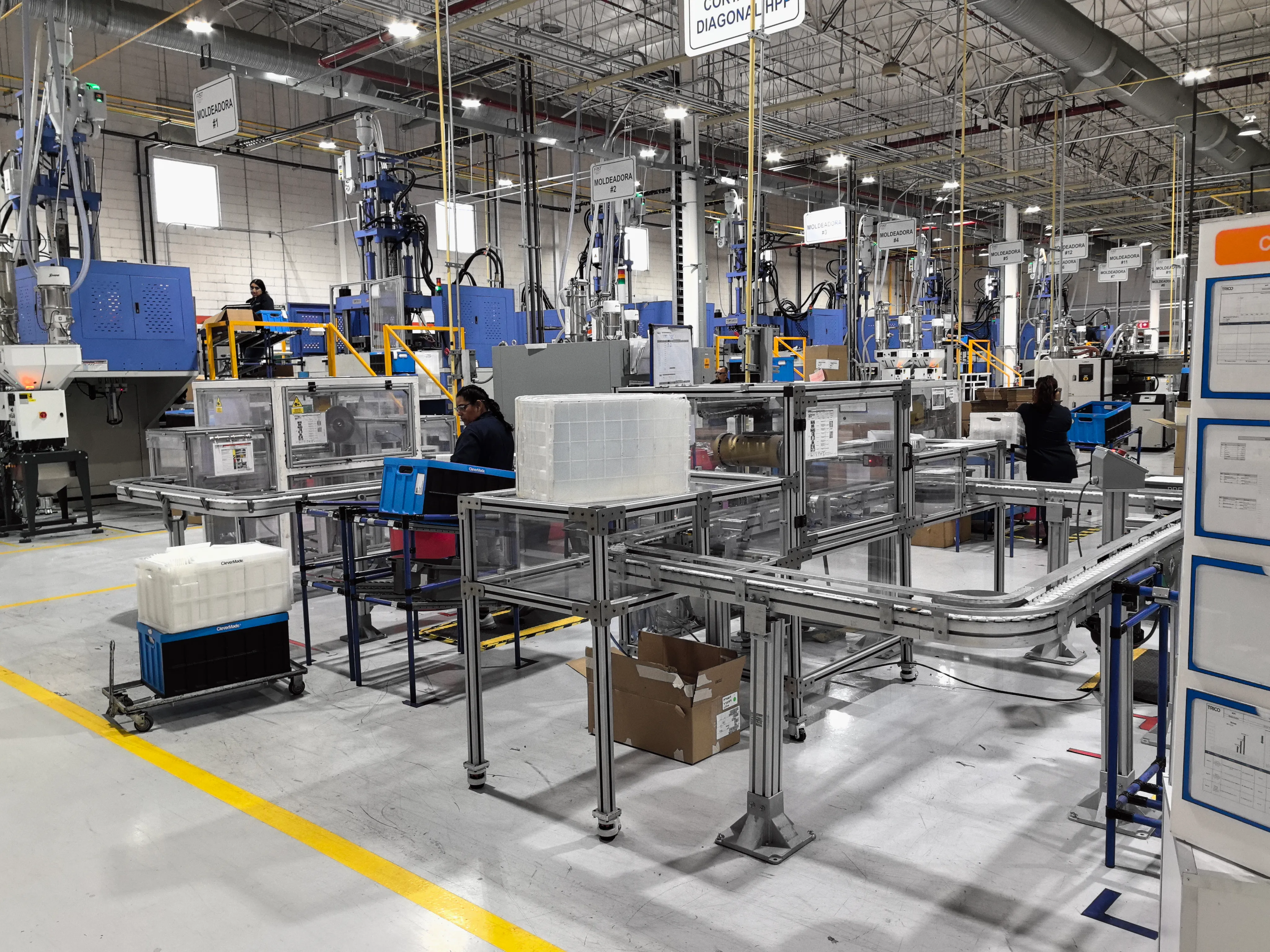 International customers touring the Deboge workshop floor with vertical injection molding machines