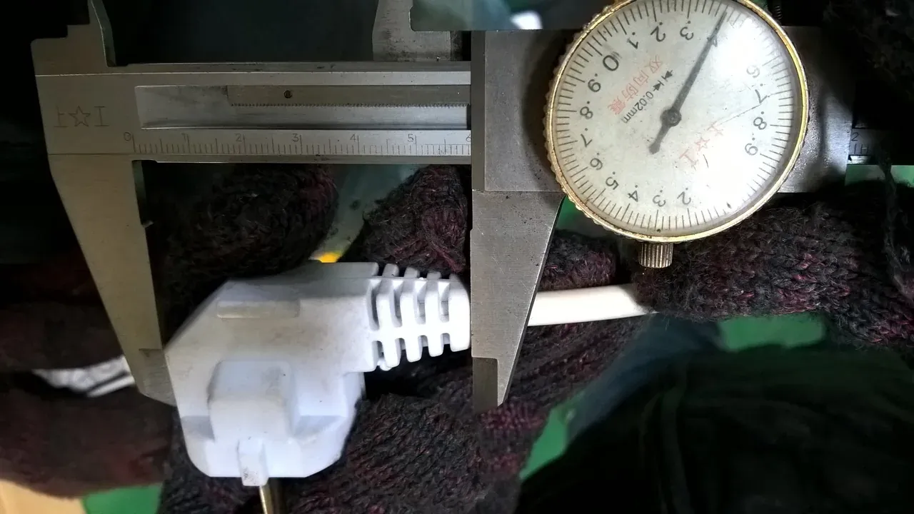 A caliper checking a molded plug body and cable strain relief in an archived trial report.