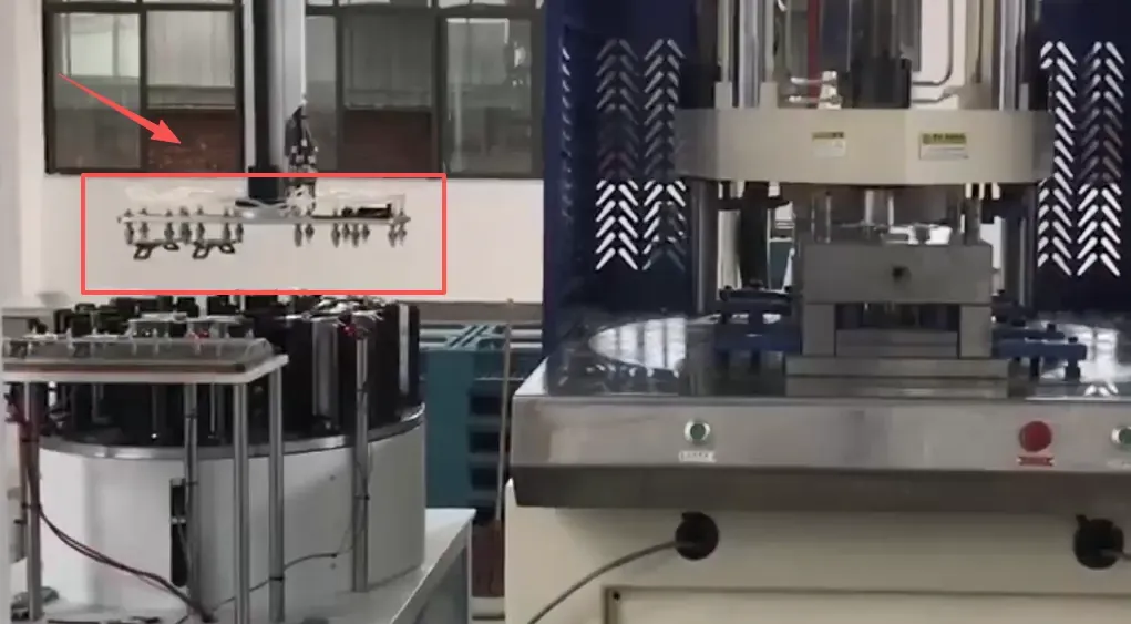Robot handling tool highlighted beside the rotary injection molding machine in the seat belt D-ring production setup